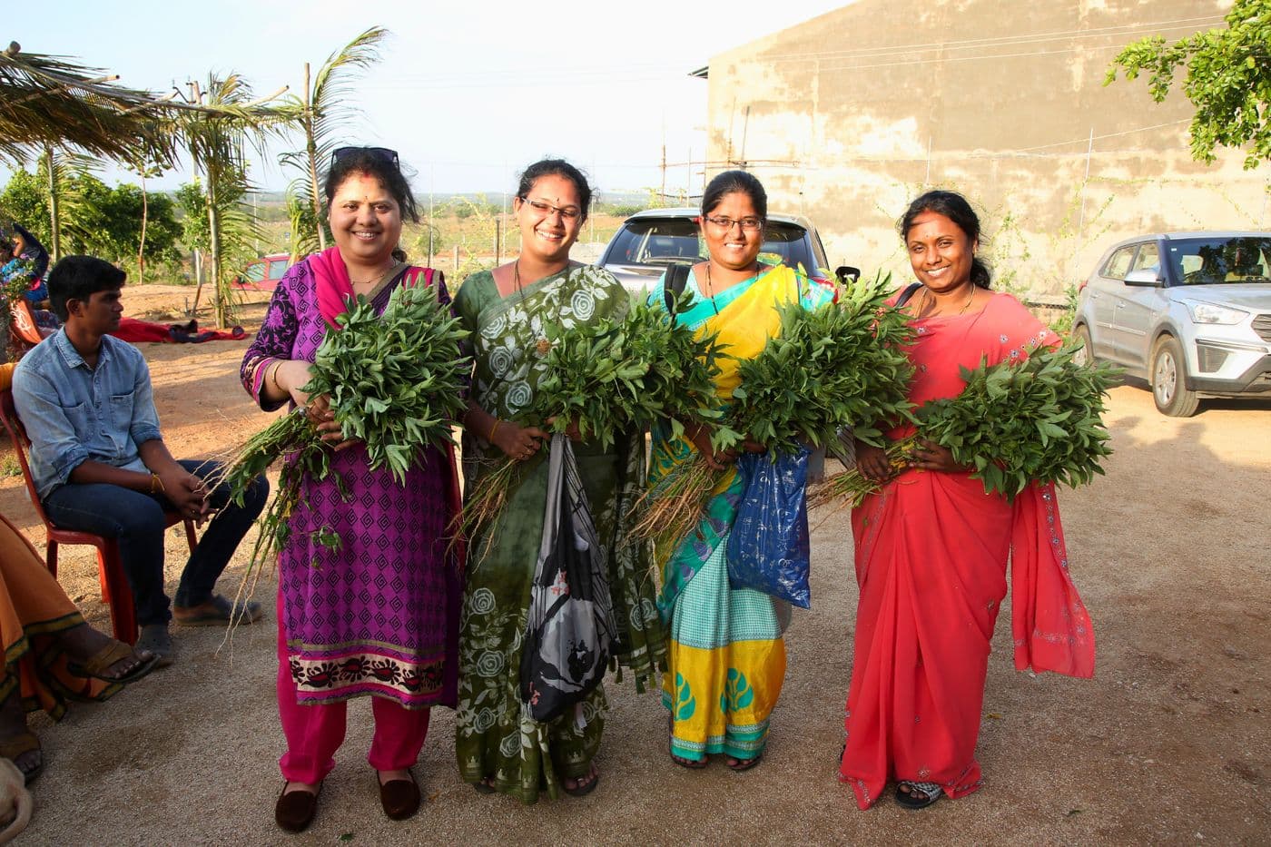 Co-farmers carrying home bundles of fresh greens