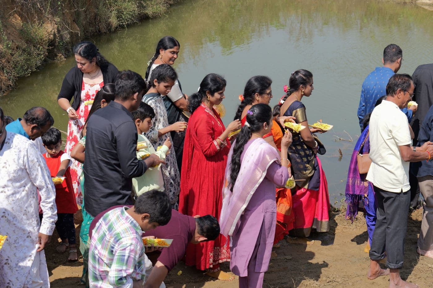 Families making offerings at the farm pond