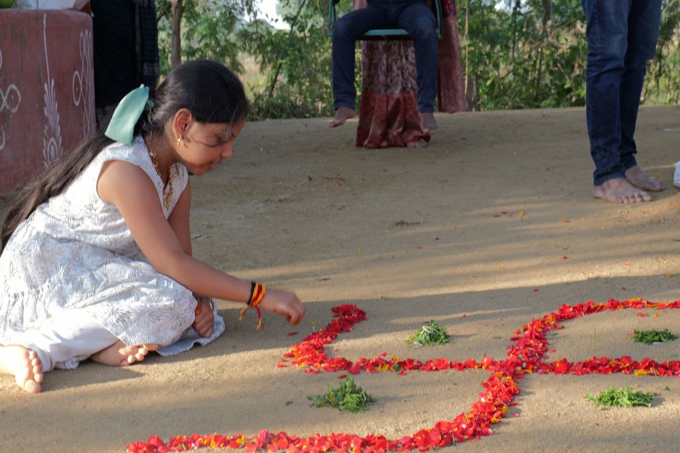 A girl laying a flower-petal rangoli